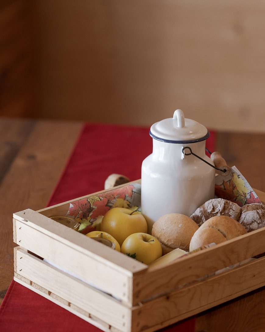 Bidone del latte, panini, mele e marmellata in una scatola di legno