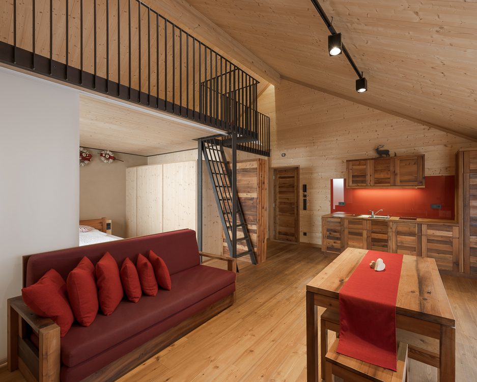 Soggiorno su 2 piani con divano, angolo cottura e tavolo in legno